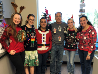 AMG employees posing in their holiday sweaters
